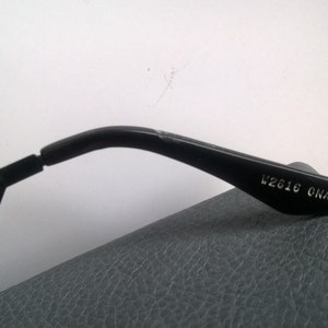 May include: Black plastic sunglasses with the text "V2016 ONAX CE" printed on the arm.