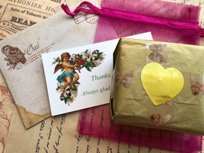 May include: A small, gold-wrapped package with a gold heart sticker and a thank you note with an angel illustration. The note says "Thanks Always glad".
