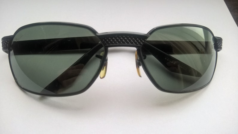 May include: Black sunglasses with a textured bridge and dark lenses.