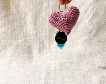 May include: A pink crocheted heart keychain with a black and blue key charm.