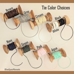 Pu&ograve; includere: Otto rocchetti di legno avvolti con cordino in vari colori con la scritta Tie Color Choices. I colori includono marrone, grigio, crema, nero, bianco, blu navy, verde, rosa e acqua. Il testo AFewSpareMoments &egrave; visibile in basso a sinistra.