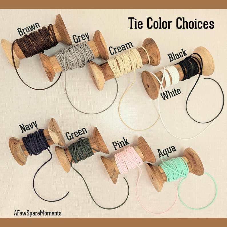 Pu&ograve; includere: Otto rocchetti di legno avvolti con cordino in vari colori con la scritta Tie Color Choices. I colori includono marrone, grigio, crema, nero, bianco, blu navy, verde, rosa e acqua. Il testo AFewSpareMoments &egrave; visibile in basso a sinistra.