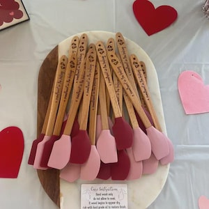 Pu&ograve; includere: Una collezione di spatole con manico in legno e teste in silicone nei toni del rosa e del rosso. Ogni manico &egrave; inciso con il testo 'a sweetheart in the baking'. Un piccolo cartoncino rettangolare in basso fornisce le istruzioni per la cura.