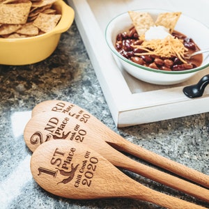 Peut inclure: Trois cuill&egrave;res en bois avec du texte grav&eacute;, indiquant "1st Place Chili Cook Off 2020", "2nd Place Cook Off 2020" et "3rd Place Cook Off 2020".