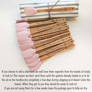 Pu&ograve; includere: Una collezione di spatole in legno con teste in silicone rosa chiaro, ciascuna con il testo inciso al laser "Morgan & Ryan's baby shower" e la data "8.05.23". Un canovaccio a righe bianche e grigie &egrave; legato con un cordoncino marrone.