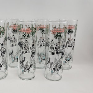 May include: Set of six clear glass drinking glasses with a black and white illustration of a city scene. The glasses feature a pink and white banner with the text "Fête de France".