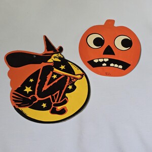 May include: Two vintage-style Halloween paper decorations. One is a circular cutout featuring a black witch in a pointed hat riding a broomstick against a yellow moon and orange background. The other is an orange pumpkin jack-o'-lantern cutout.
