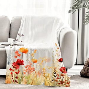 May include: White throw blanket with a watercolor floral design featuring red, orange, and yellow flowers and green stems on a white background.