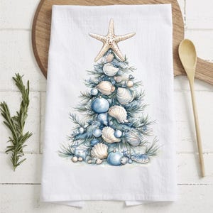 May include: A white kitchen towel with a blue and white seashell Christmas tree design. The tree is decorated with blue ornaments and a starfish on top.