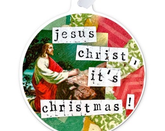 Puede incluir: Un adorno redondo y blanco con un collage de recortes de papel de colores y una imagen de Jesús. El texto en el adorno dice "jesus christ it's christmas!"