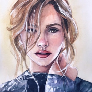 May include: A watercolor painting of a person with light brown hair, brown eyes, and pink lips. The subject wears a dark blue sweater and has loose strands of hair framing their face. The artwork features soft brushstrokes and a light beige background.