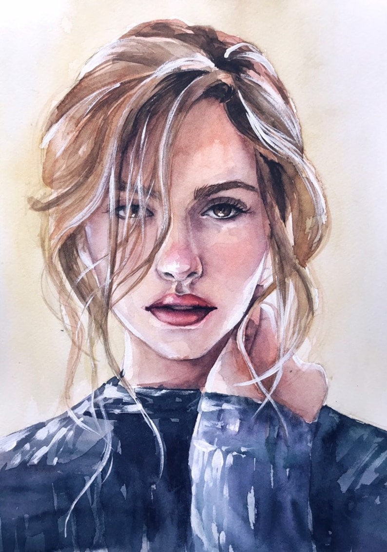 May include: A watercolor painting of a person with light brown hair, brown eyes, and pink lips. The subject wears a dark blue sweater and has loose strands of hair framing their face. The artwork features soft brushstrokes and a light beige background.