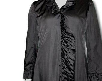 Op de afbeelding: Zwarte satijnen top met lange mouwen, een gerimpelde kraag en voorkant. De top heeft een waterval-ruffle detail in het midden en bij de manchetten. Het kledingstuk heeft een klassiek, elegant ontwerp.