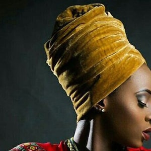 May include: A mustard yellow velvet turban headwrap. The turban is wrapped in a thick, luxurious fabric.
