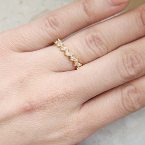 Könnte beinhalten: Ein Goldring mit einer Reihe von klaren Baguette-Steinen.