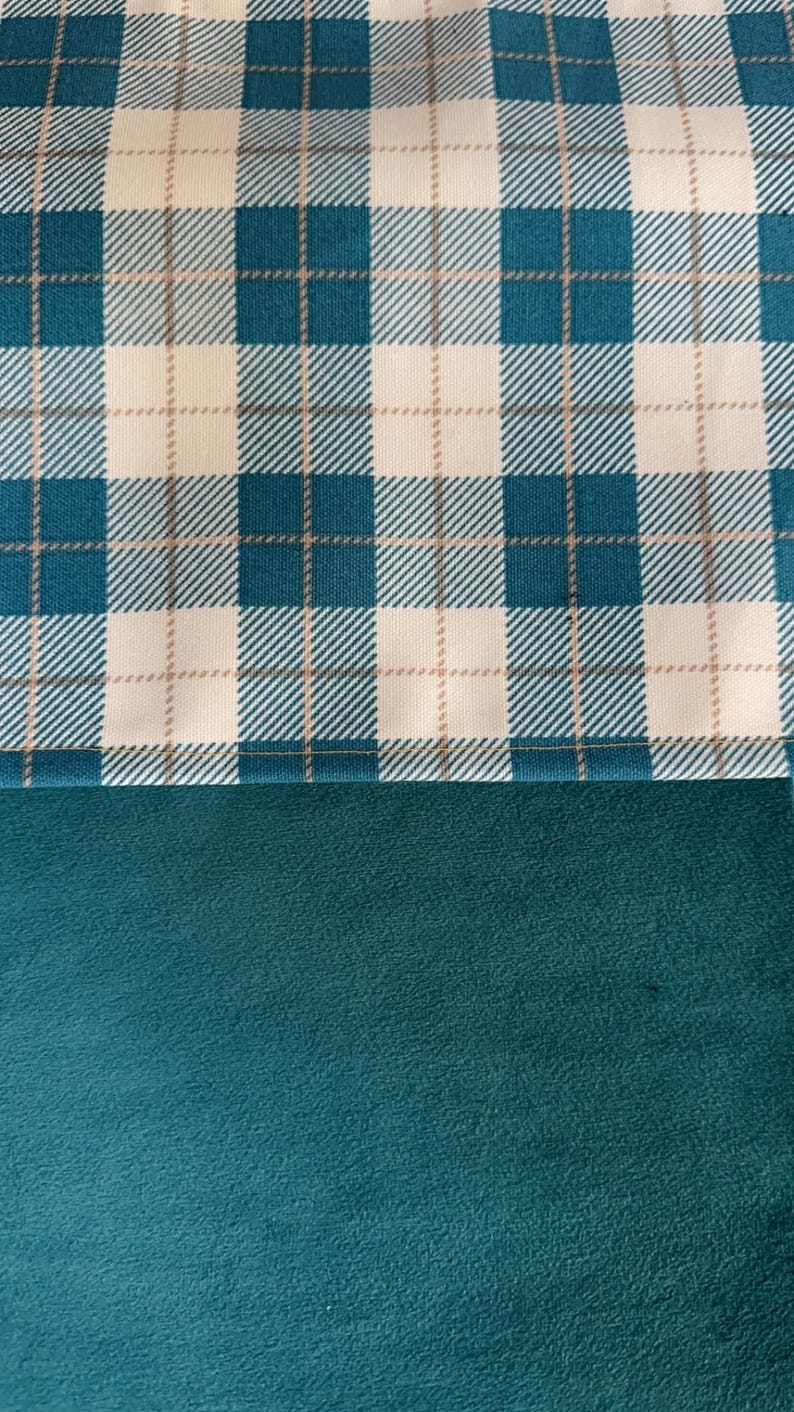 May include: A close-up of a teal and white plaid fabric. The plaid pattern features teal and beige lines, creating a classic checkered design. Below the plaid is a solid teal fabric with a soft, textured appearance. The image showcases a textile.