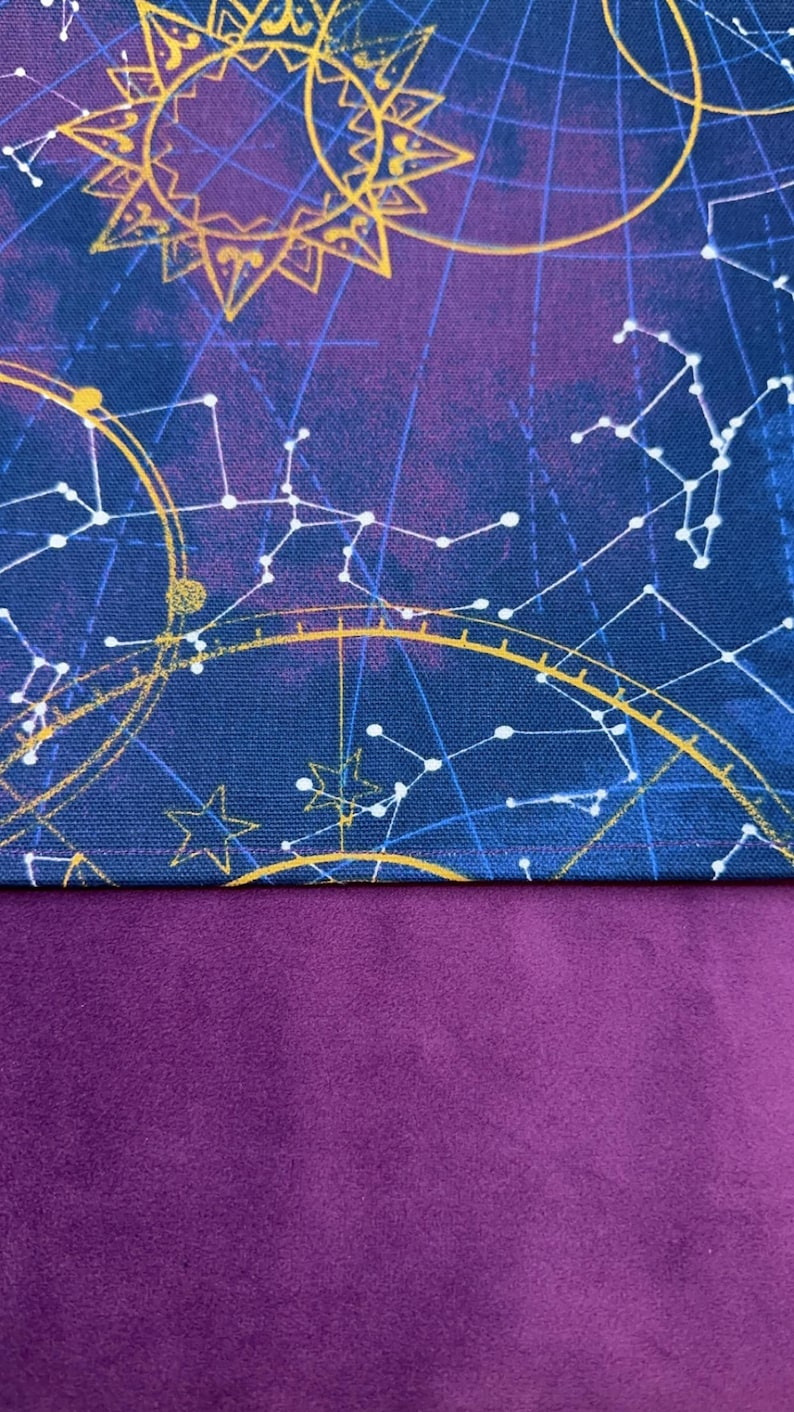 May include: A celestial-themed fabric featuring a deep blue background with gold and white constellations, sunbursts, and celestial map designs. The lower portion of the fabric is a solid, rich purple color. This fabric is suitable for various crafting projects.
