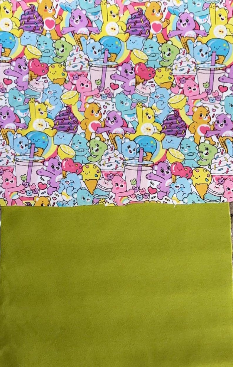May include: A colorful fabric featuring a pattern of cartoon bears with ice cream, cupcakes, and rainbows. The bears are in various colors, set against a white background. Below is a solid green fabric.