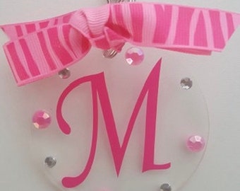 May include: Pink and white striped ribbon attached to a clear acrylic keychain with a pink letter M and pink rhinestones.