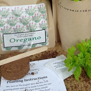 May include: A kit for growing your own oregano. The kit includes a brown paper bag with a plant inside, a clear plastic dome, a small wooden stick, a brown seed disc, and a white paper with instructions. The paper bag has the text "The English Spice Garden Grow your own Oregano Just Add Water" printed on it.