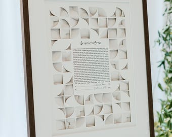 May include: A framed artwork with a dark brown wooden frame, displayed on a silver easel. The artwork features a white background with a geometric design of squares and semi-circles. Text is visible in the center of the artwork.