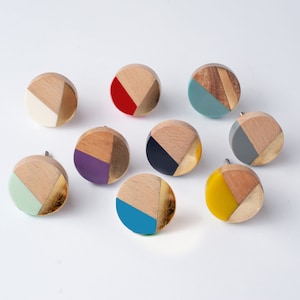 May include: Assortment of ten round wooden knobs with geometric patterns and gold accents. Each knob features a different colour combination, including teal, purple, red, yellow, and black.