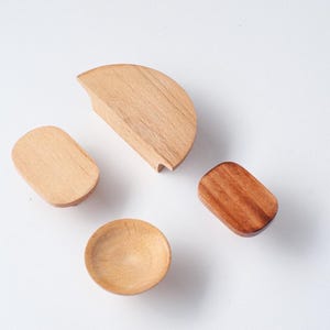 May include: Four wooden objects of different shapes are displayed on a white background. They include a half-circle, two ovals, and a small bowl. The wood colours vary from light to medium brown.