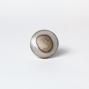 May include: A circular cabinet knob featuring a light grey resin outer layer and a natural wood centre. The wood grain is visible. This knob is a decorative hardware element, suitable for furniture.
