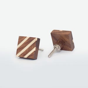 May include: Two square wooden cabinet knobs. The knobs are dark brown with diagonal cream stripes. Each has a silver screw for fitting. The knobs are shown against a white background.