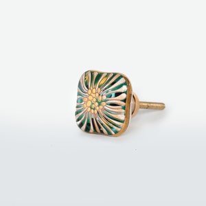 May include: Square ceramic cabinet knob with a green and gold floral design.