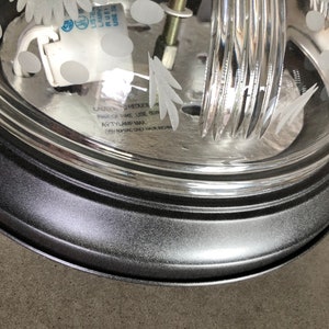 May include: A black metal ceiling light fitting with a clear glass shade featuring a floral design. The shade has a textured surface and a black metal rim. The light fitting has a white electrical socket and a warning label that reads "CAUTION: TO REDUCE RISK OF FIRE, USE ONLY TYPE "A" BULB, MAX 60W."