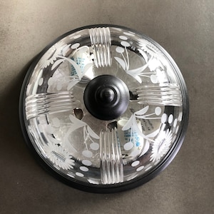May include: A black ceiling light fitting with a clear glass shade. The shade features a decorative etched floral pattern and is accented with a black metal trim.