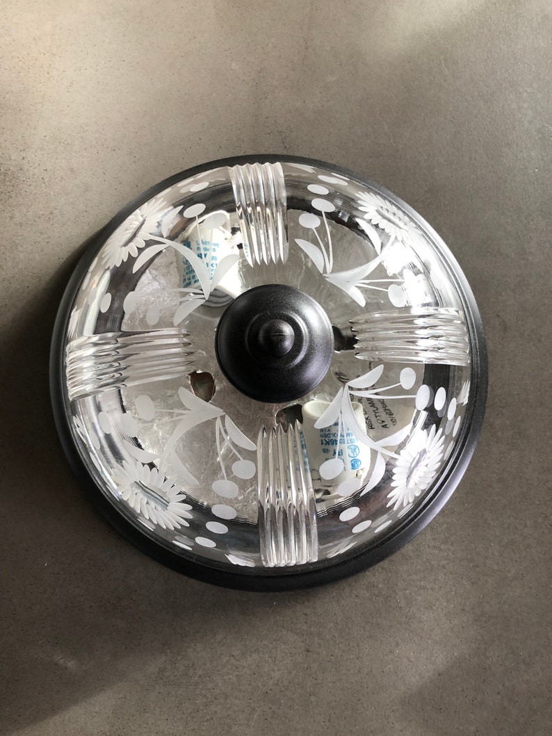 May include: A black ceiling light fitting with a clear glass shade. The shade features a decorative etched floral pattern and is accented with a black metal trim.