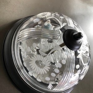 May include: A black and clear glass ceiling light fixture with a floral design. The fixture has a dome-shaped glass shade with a black metal base.