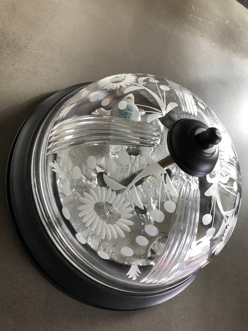 May include: A black and clear glass ceiling light fixture with a floral design. The fixture has a dome-shaped glass shade with a black metal base.