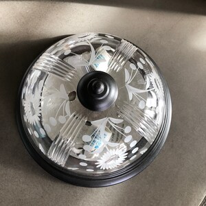 May include: A black ceiling light fitting with a clear glass shade featuring a floral design. The shade has a textured, ribbed pattern and white polka dots.