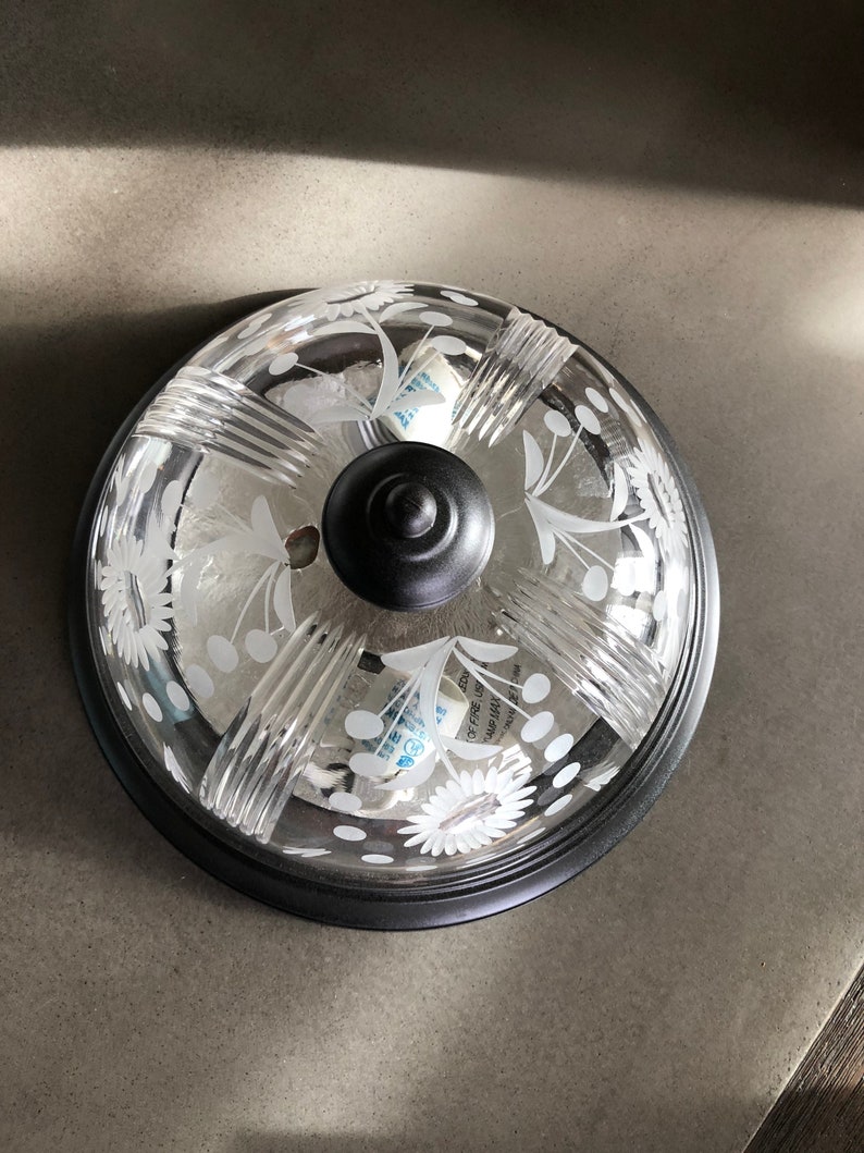 May include: A black ceiling light fitting with a clear glass shade featuring a floral design. The shade has a textured, ribbed pattern and white polka dots.