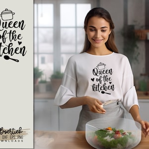 May include: A white t-shirt with black text that reads "Queen of the kitchen" with a small pot and spoon graphic. The text is surrounded by two small hearts. A woman is wearing the shirt and preparing a salad.