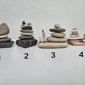 May include: Four different rock stacks, each with a unique arrangement of stones. The stacks are numbered 1 through 4, and are arranged on a white surface.