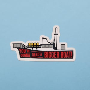 May include: A white sticker with a black and white illustration of a boat with the text "You're gonna need a bigger boat!" in red.