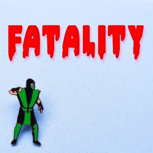 May include: A green and black ninja figure with a white mask, standing on a light blue background with the word "FATALITY" in red letters above it.