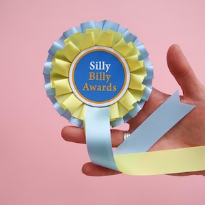 Könnte beinhalten: Eine blaue und gelbe Rosette mit einem blauen Kreis in der Mitte, auf dem "Silly Billy Awards" steht.