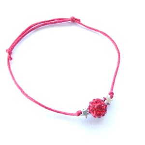 May include: A red string bracelet with a red rhinestone ball charm and three silver star charms.
