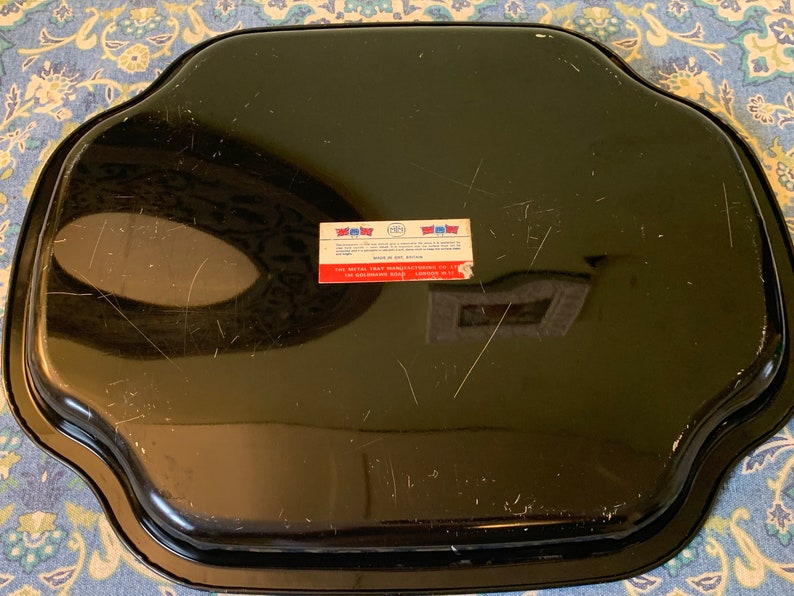 Pu&ograve; includere: Vassoio da portata in metallo nero con bordo ondulato. Il vassoio ha un adesivo sul fondo che recita "The Metal Tray Manufacturing Co., Inc. 412 Goldens Bridge Rd.  Golden's Bridge, N.Y."
