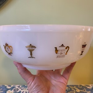 Peut inclure: Bol en céramique blanche avec des motifs dorés et rouges de théières et de tasses. Le bol a deux anses.