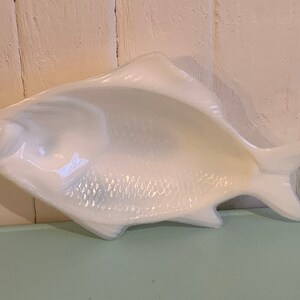 Peut inclure: Plat en céramique blanche en forme de poisson. Le plat a une surface texturée détaillée qui ressemble à des écailles de poisson.