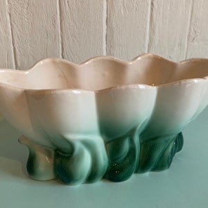 Peut inclure: Un pot en céramique blanche avec un glaçage vert. Le pot est en forme de fleur avec cinq pétales et a un bord festonné. La base du pot est en forme de cinq feuilles vertes.