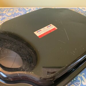 Pu&ograve; includere: Teglia da forno in metallo nero con bordo ondulato. La teglia ha un adesivo sul fondo che recita "New York Metal Ware Corp.  Made in USA".