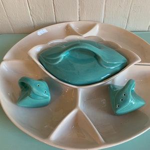 Peut inclure: Un plat de service en céramique blanche avec cinq sections et un couvercle turquoise. Le plat est accompagné de deux salières et poivrières turquoise.