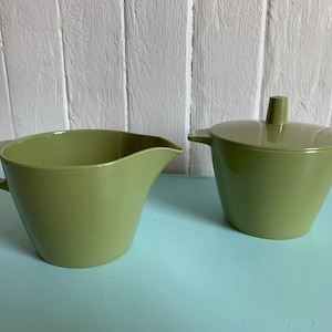 Peut inclure: Un ensemble de crémier et de sucrier en céramique verte. Le crémier a une poignée et un bec verseur. Le sucrier a un couvercle.